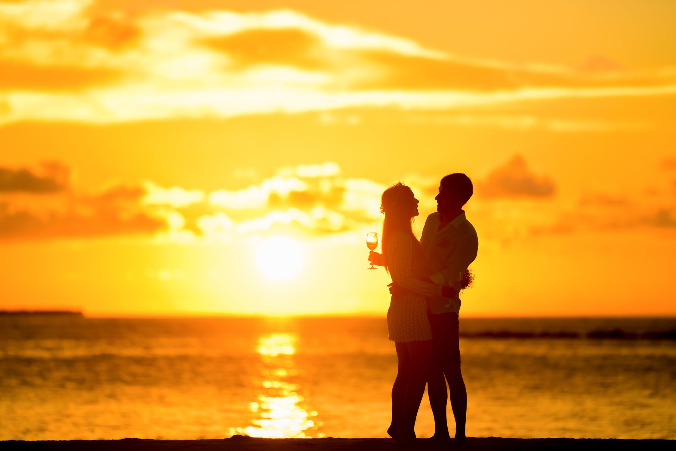 A man with a Cebuana by the beach with the sun setting in the background.